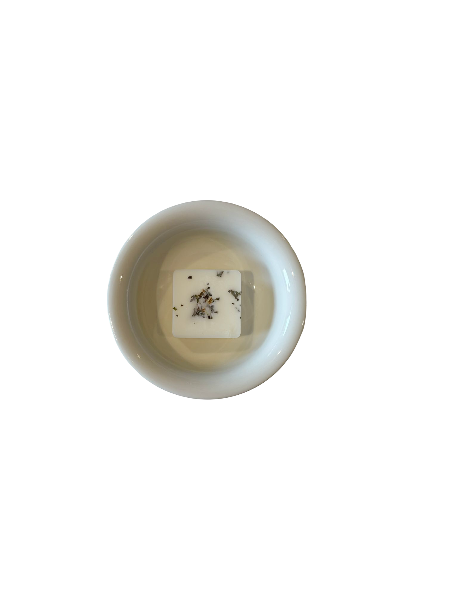 Small white dish with a square white soy wax melt candle inside on a light beige background